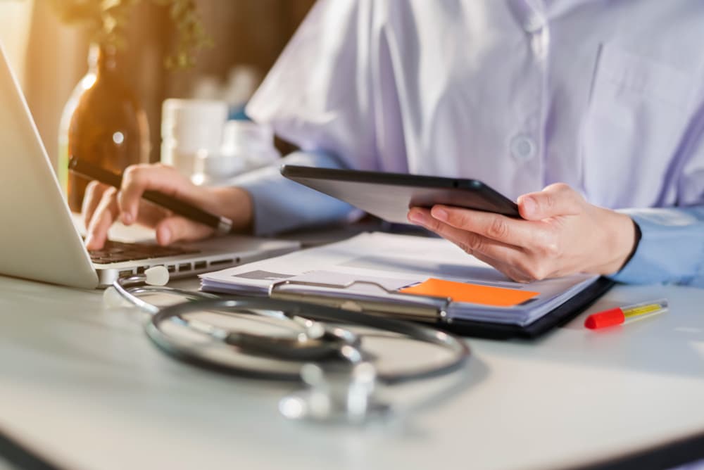 Female doctor working on desk with laptop computer and paperwork in the office. Medical and doctor concept.