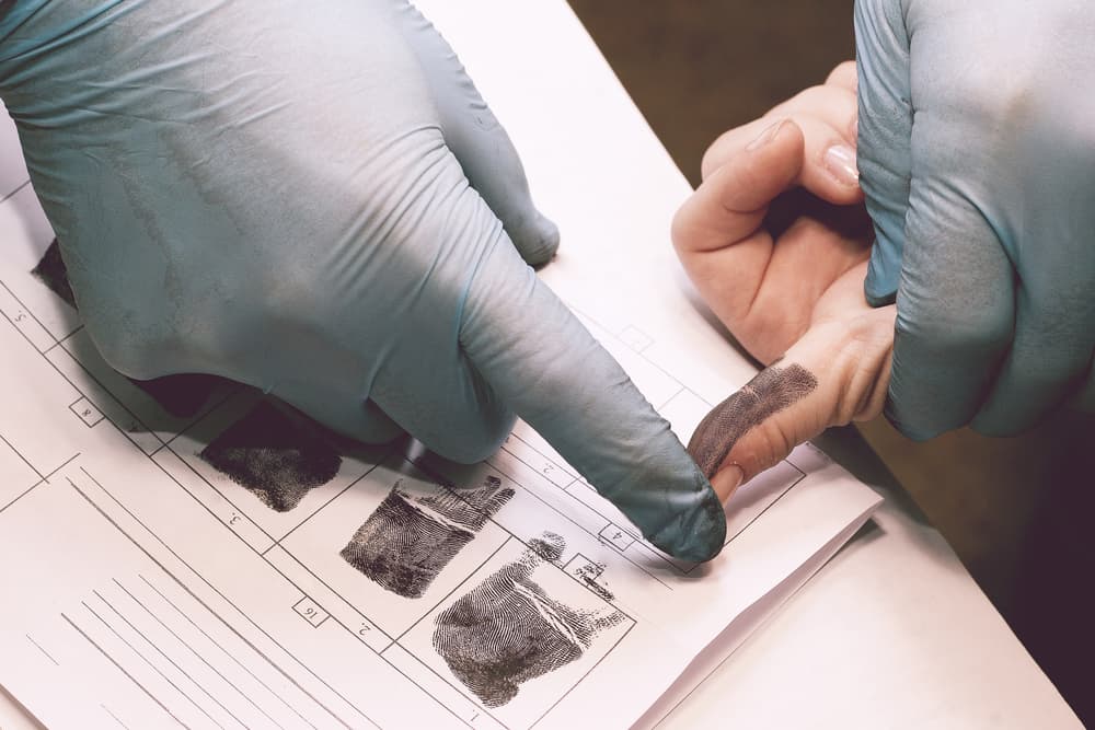 Investigator collecting fingerprints from suspect in criminal investigation.