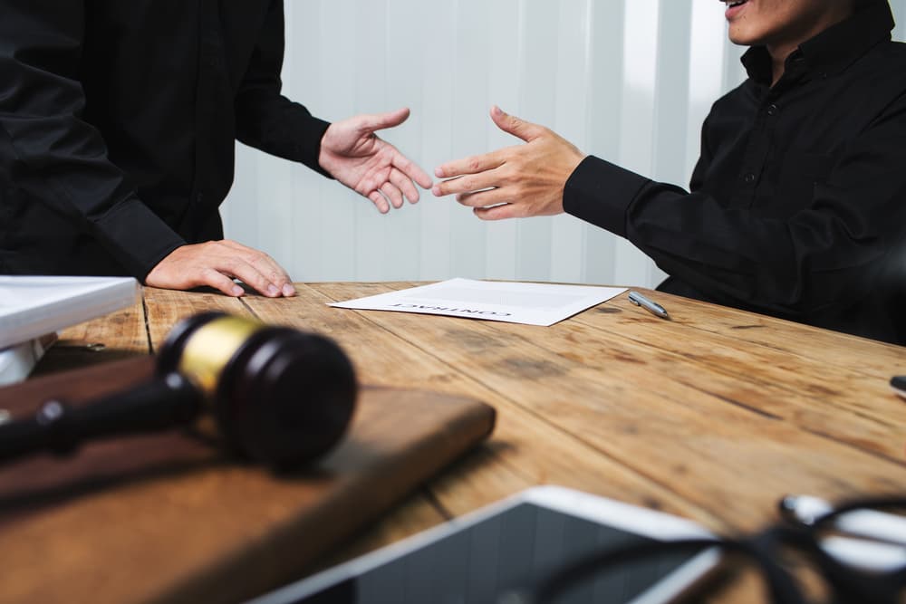 Two attorneys discussing a case with a gavel and documents on the table.