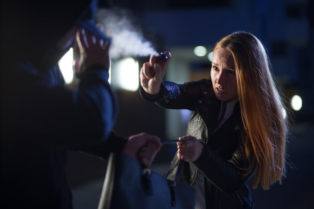 Woman defending herself against a thief at night in an urban setting.