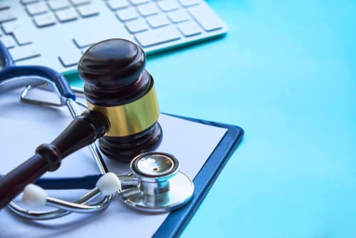 stethoscope and gavel on clipboard next to keyboard on desk