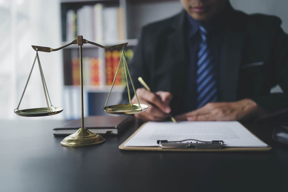 A male lawyer working with contract papers and a wooden gavel on a table in a courtroom. Justice and law concept.