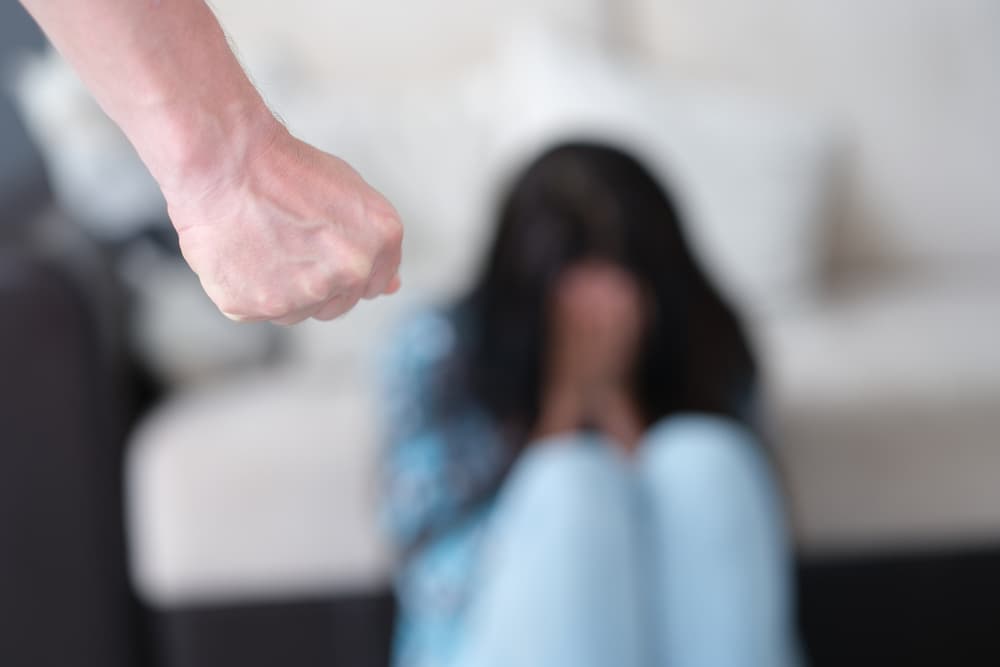Man stands with fist clenched against background of crying woman