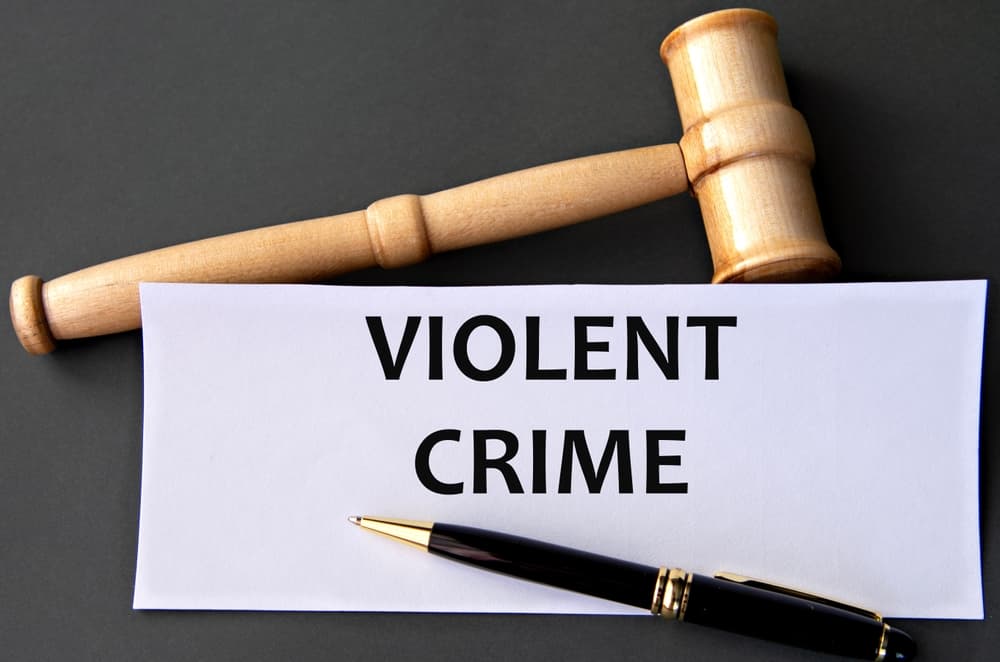 VIOLENT CRIME - words on white paper on dark background with judge's gavel.