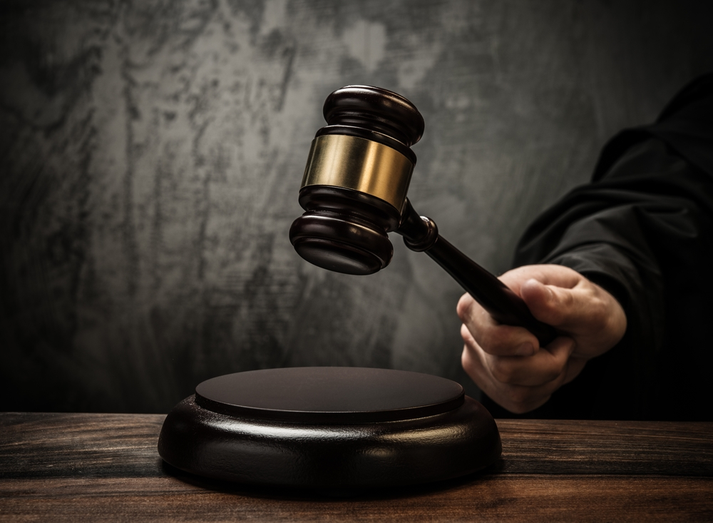 Judge holding gavel poised above wooden table in courtroom