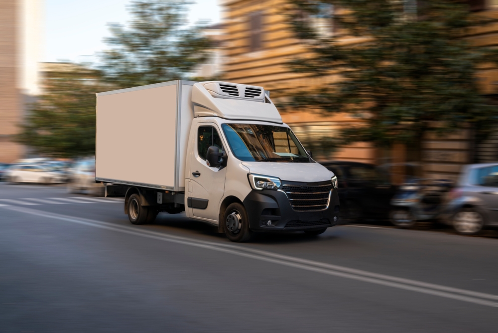 Commercial delivery truck driving through city street, highlighting vehicle regulations in truck accident cases