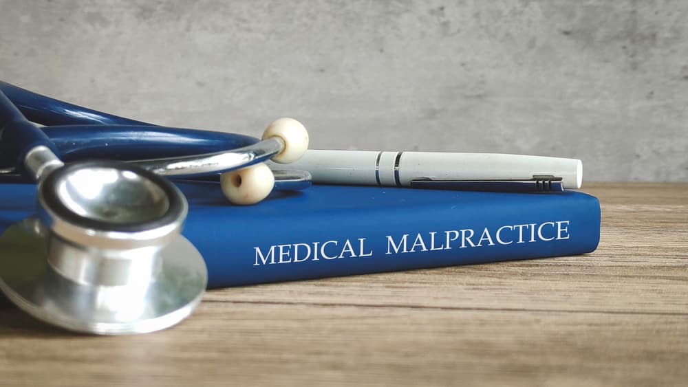 Stethoscope resting on a book labeled medical malpractice with a pen on top, symbolizing wrongful death claims from medical errors
