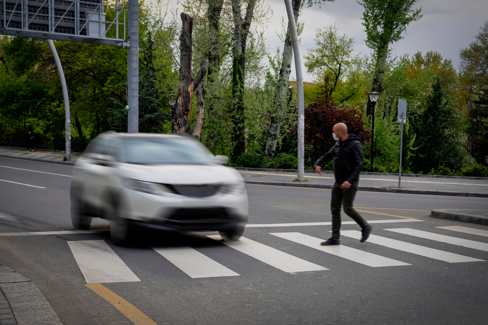 Pedestrian narrowly avoiding a car while walking across a marked crosswalk